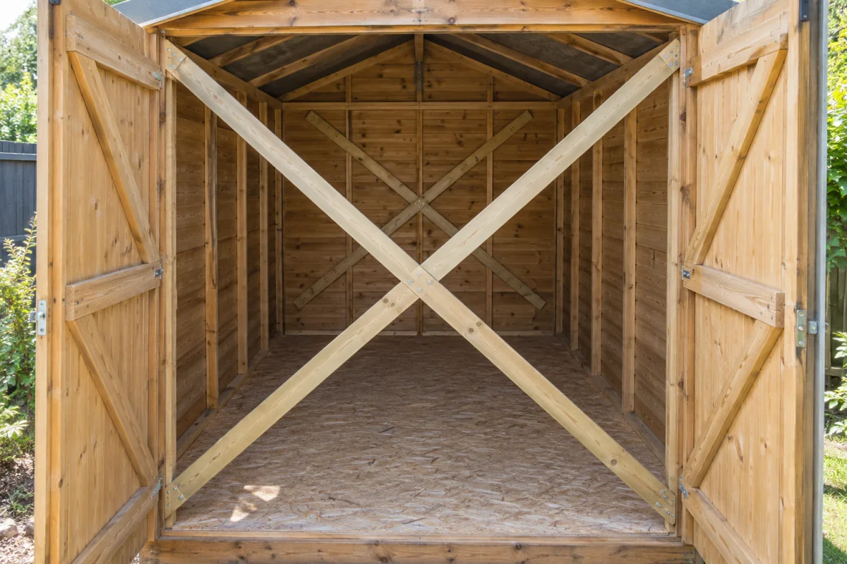 Empty timber shed with temporary diagonal braces across the walls and wide door opening before a move